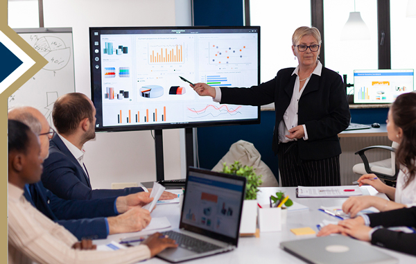 professional female presents data from a digital screen to colleagues seated at conference table  (Image by DCStudio on Freepik)