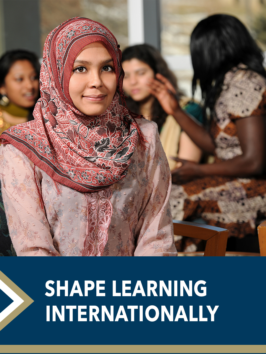 &quot;Shape learning internationally.&quot; - group of Indonesian females talk in the background, subject in front makes eye contact with camera
