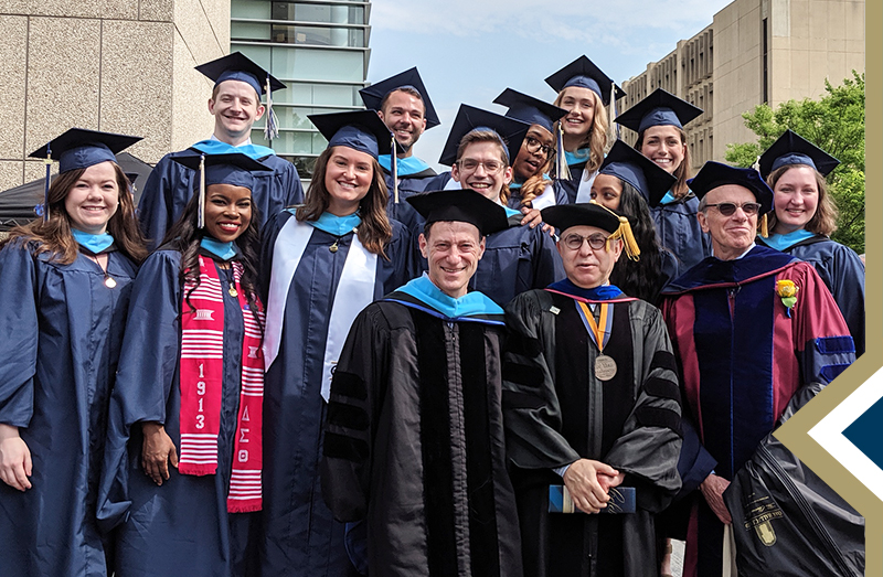program graduates and faculty in regalia pose for group photo at commencement