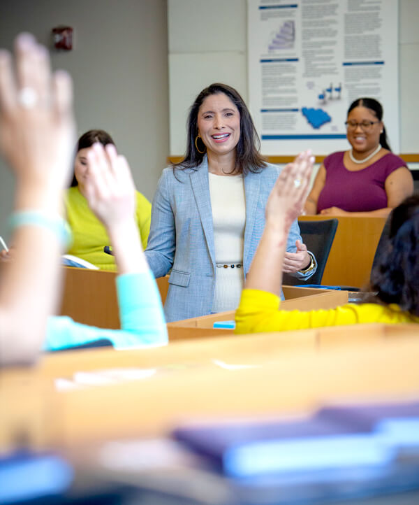 GSEHD professor Dr. Natalie Milman stands in middle of classroom, students' hands are raised in foreground