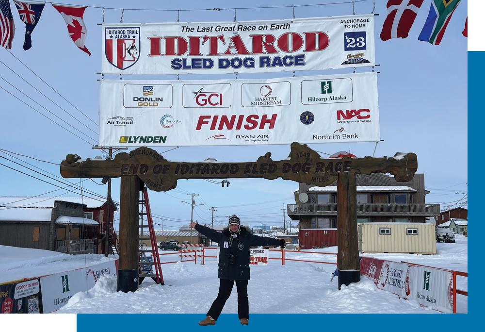 Juli Westrich poses under Iditarod banner