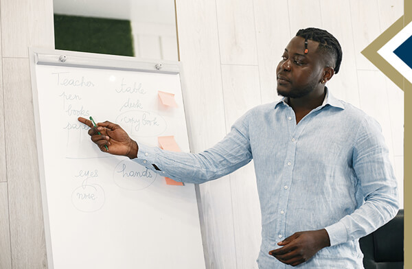 Professional male points to words on a large sketch pad in classroom