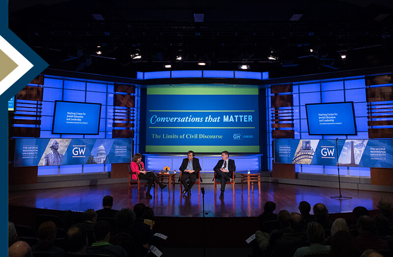 three speakers sit on large dark stage with media screens in background that reads "Conversations That Matter: The Limits of Civil Discourse"
