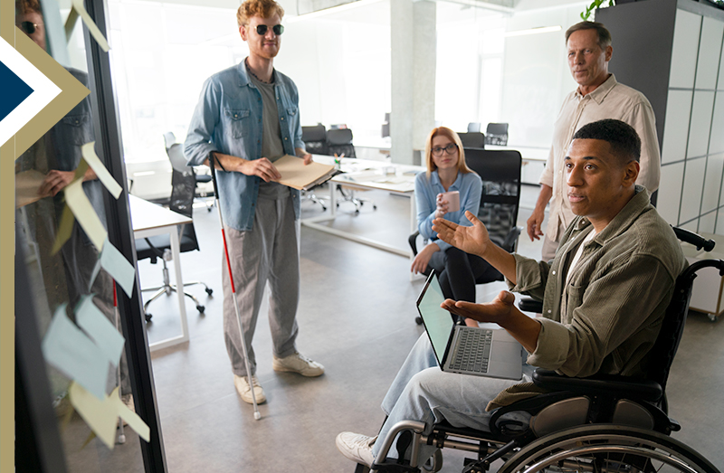 Male in wheelchair leads a strategy meeting on how to make a product accessible for all users; a man with a walking cane also shares his experience - Image by Freepik