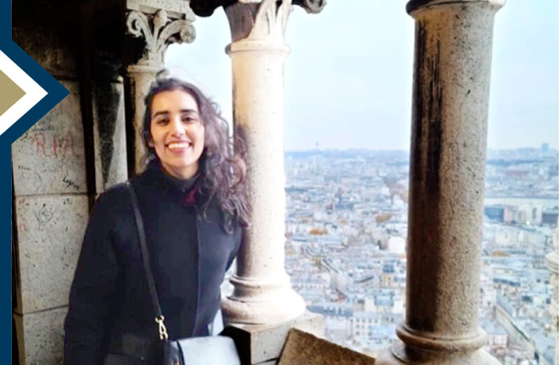 Maha Malik smiles for camera with ocean in the background in Paris during UNESCO fellowship