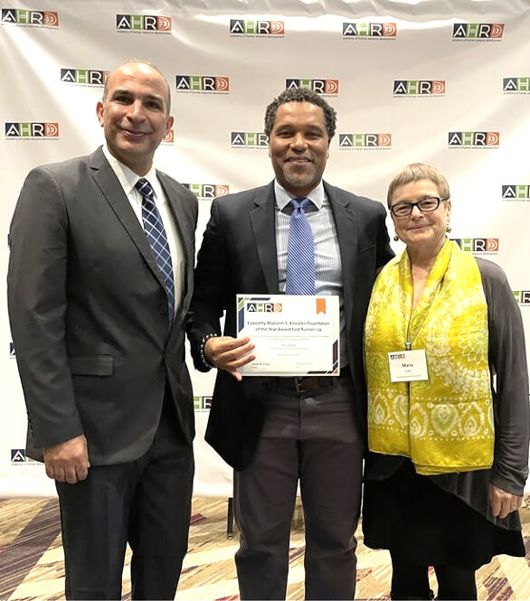 Dr. Ricco Hall (center) receives the Malcolm S. Knowles Dissertation of the Year Award First-Runner Up (with Dissertation Chair Dr. Maria Cseh on right)