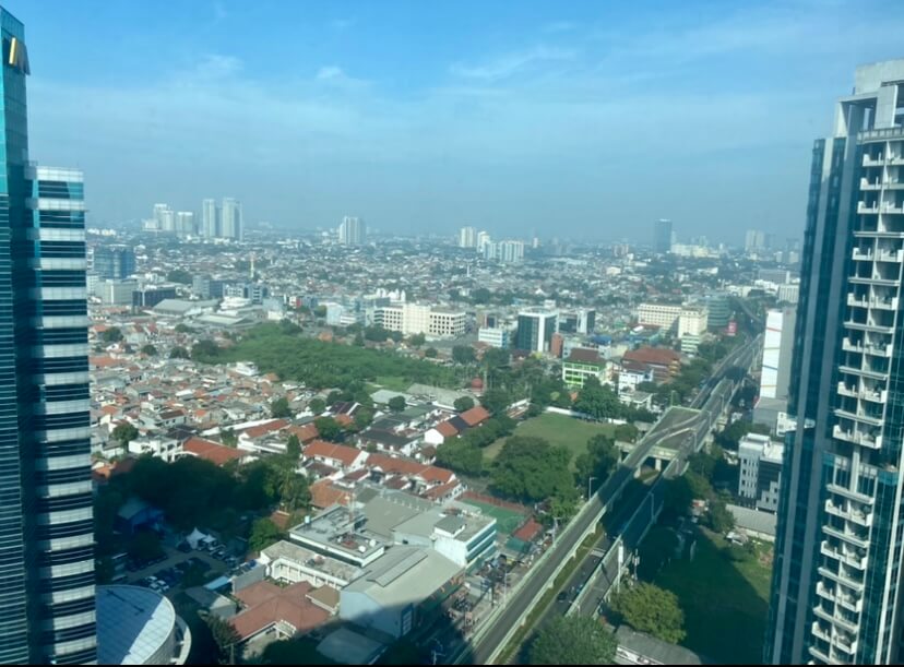 An aerial view of the continuously fast-paced city of Jakarta framed by two skyscrapers on the left and right of the photo
