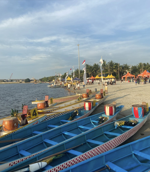Canoe style boats docked along the edge of the short at an Indonesia Independence Day festival