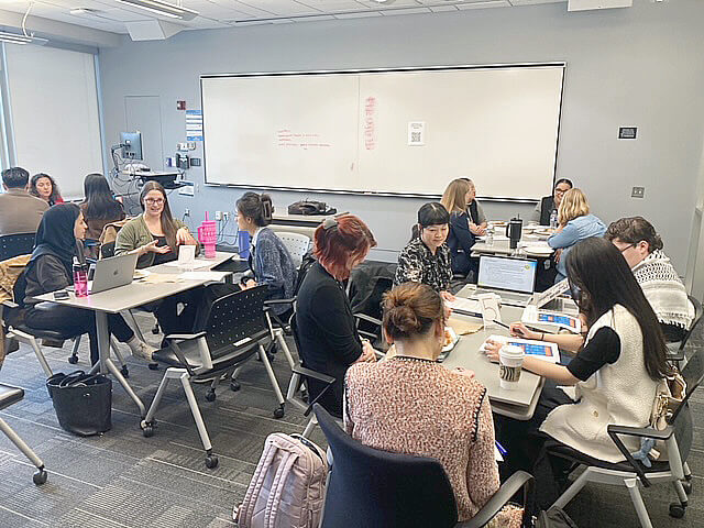 participants of the Research Kaleidoscope event discuss their projects in small groups seated at tables