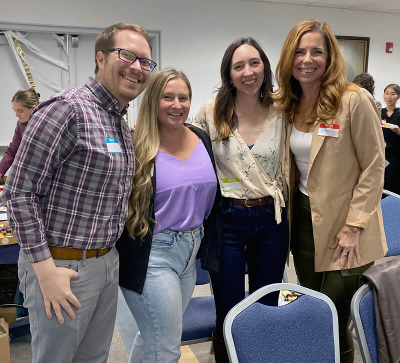 three students pose for a photo with Dr. DeRaedt after the research symposium