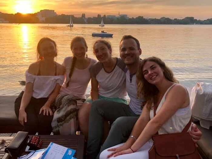 Kyle Hall poses for photo with friends on a patio with the water in the background