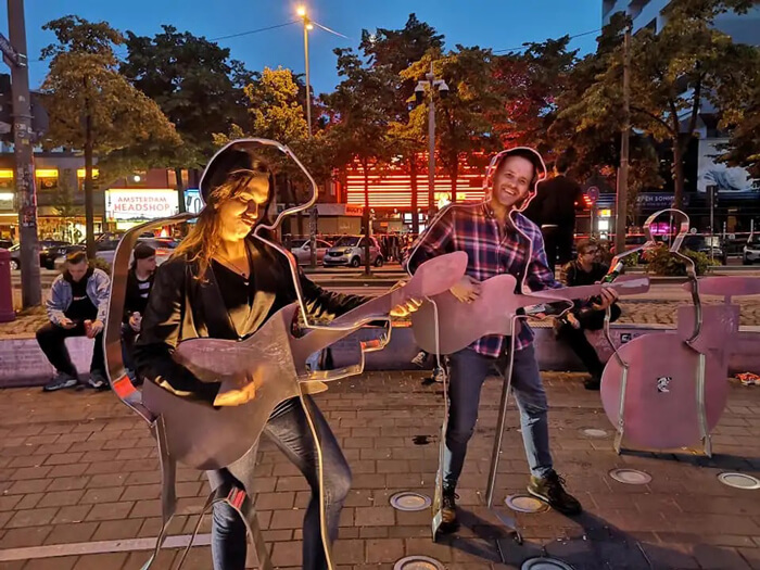 Kyle and a friend pose in a metal musical sculpture on street in Germany