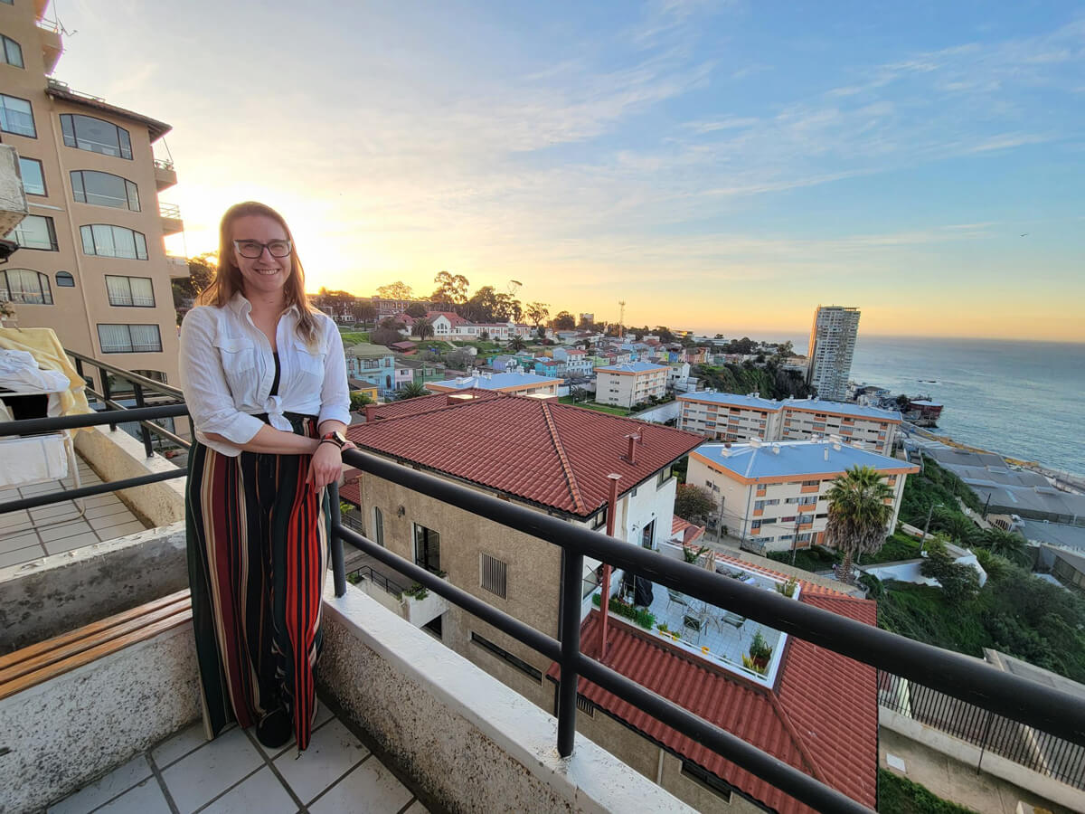 Caroline poses for photo on a balcony in Valparaíso with the town and ocean in the background