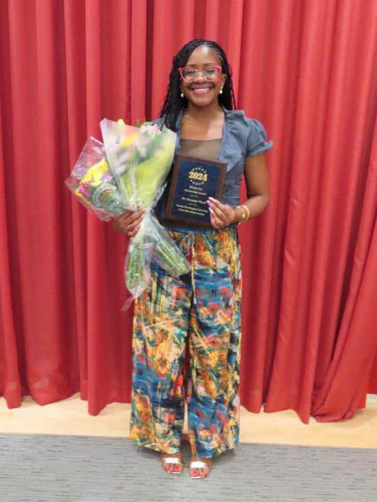 Dr. Maranda Ward smiles for photo with Rising Star award and bouquet of flowers