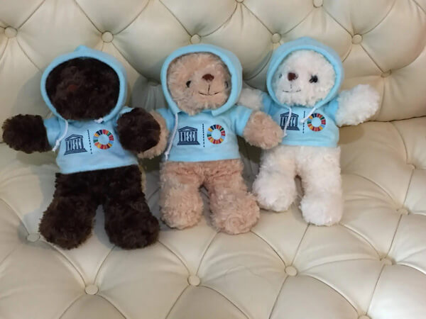 three teddy bears wearing hoodies with UNESCO logos