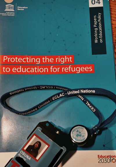 Renny's lanyard from ECLAC conference lays on top of copy of working paper titled, "Protecting the right to education for refugees"