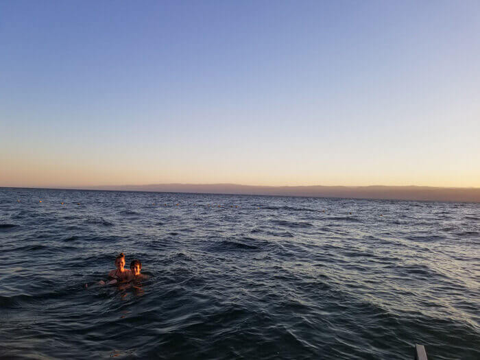 Justin Rotundo and a friend smile for a photo while swimming in the Dead Sea
