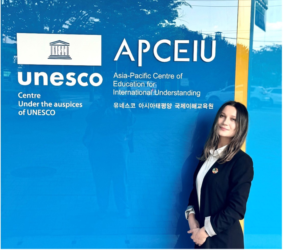 Tishkus poses in front of UNESCO APCEIU main entrance sign