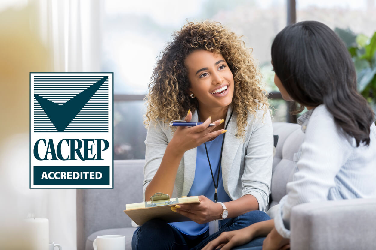 CACREP Accredited (photo of counselor speaking to client)