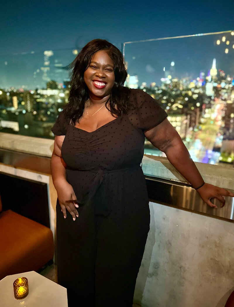Micha Aime poses for photo with city skyline in the distance