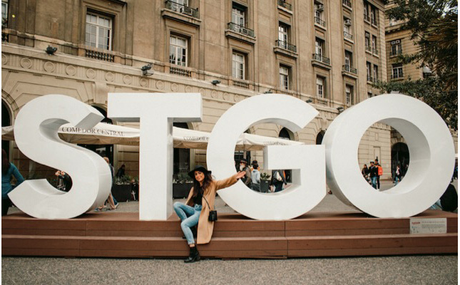 Renny poses for a photo in front of giant letters "STGO" at Plaza de Armas in Santiago’s Historic Center