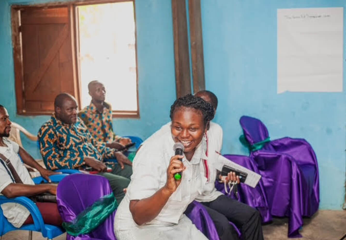 IIES speaker enthusiastically speaks into the microphone, attendees in the background