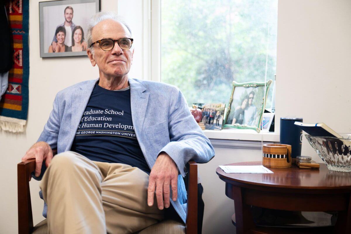 Dean Feuer sits in office chair; Photo Credit: Arwen Clemans, Senior Photo Editor, The Hatchet