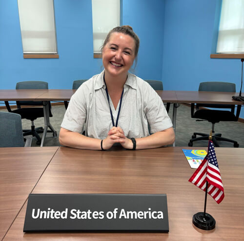 Isabelle Cooksey sitting at the United States of America representative's seat at the Model UNESCO Conference Hall at the Global Citizen Campus at APCEIU