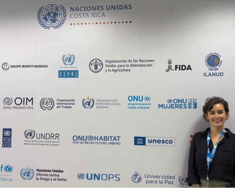 Lily poses for a photo in front of a step-and-repeat banner with various logos At the UNESCO office in San Jose Costa Rica