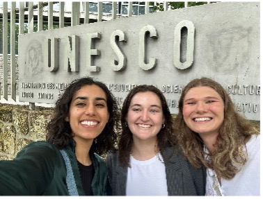 Meagan O'Malley poses for selfie in front of UNESCO sign with two new colleagues