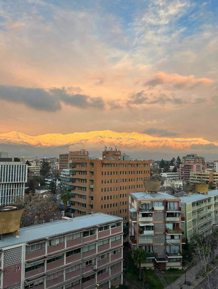 sunset highlights the snow on the mountains in the distance of the city