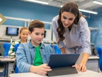 teacher leans forward to assist middle school student on tablet (Image credit: Freepik)