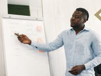 Professional male points to words on a large sketch pad in classroom