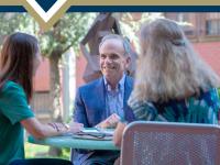 Dr. Feuer speaks to two GSEHD students at outdoor table