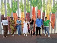 Dr. Eakle and Students pose for group photo in front of carrot mural at the DC Alley Museum