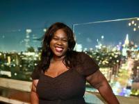 Micha Aime poses for photo with city skyline in the distance