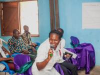 IIES speaker enthusiastically speaks into the microphone, attendees in the background