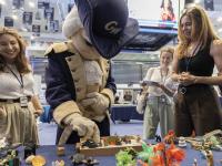 George (mascot) tries out the sand tray at a booth manned by play therapy specialists, including graduate student Haley Giles (left) and Clinical Assistant Professor of Counseling and Human Development Mary DeRaedt (right). 