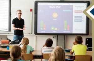 Teacher leads class in educational video game projected on board in front of class