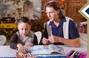 young male camp counselor assists boy with puzzle
