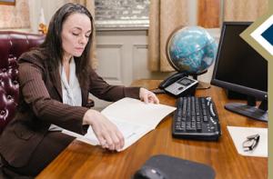 professional female reviews document in her office, globe on the desk in background