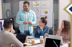 casually dressed group of professionals review charts and their laptops around a conference table - photo credit: Freepik