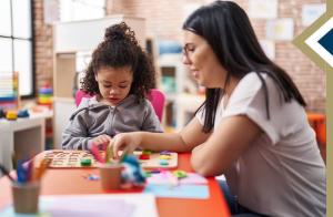 Image by krakenimages.com on Freepik of counselor and toddler playing with puzzle game sitting at table
