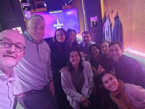O'Malley joins her team for a group selfie-style photo, purple lights cast purple glow over photo