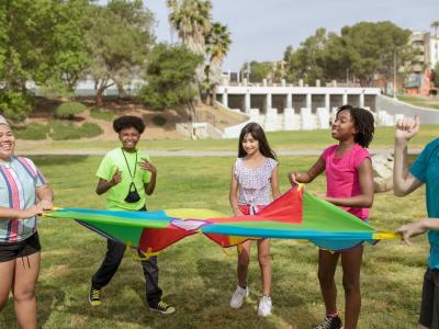 elementary age children playing with colored tarp outside