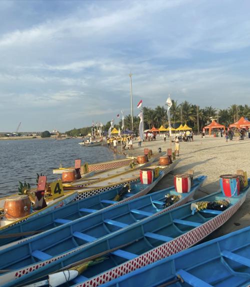 Canoe style boats docked along the edge of the short at an Indonesia Independence Day festival