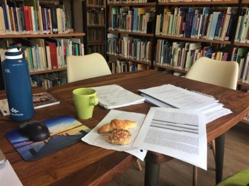 papers, snacks, etc spread across a table in a library