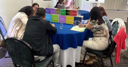 Group sits at table working on a model of the values of the project from San Francisco School, a Western Regional School of La Fortuna: "Finca Tierra Prometida as a Cradle of Entrepreneurship”
