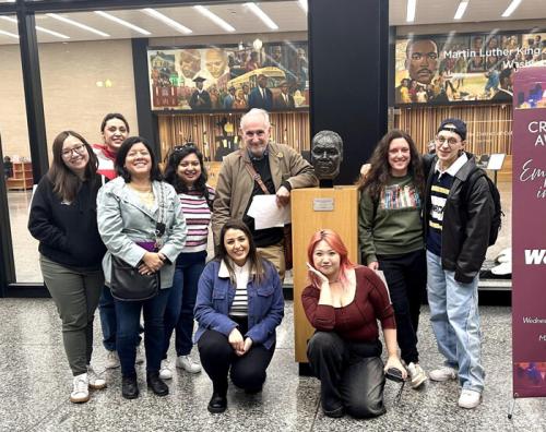 PhD students and Dr. Eakle pose for a group photo with a bust of MLK, Jr. at the MLK Library