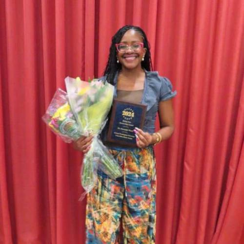 Dr. Maranda Ward smiles for photo with Rising Star award and bouquet of flowers